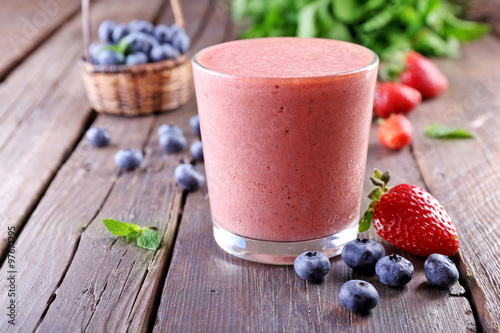 A glass of fresh cold smoothie with berries, on wooden background