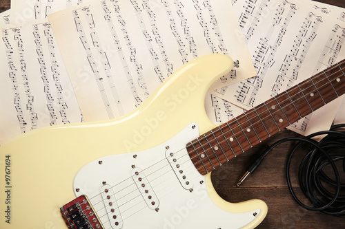 Electric guitar with musical notes on wooden background