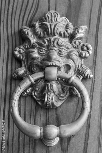 Antique door knocker shaped like a demon on an old door
