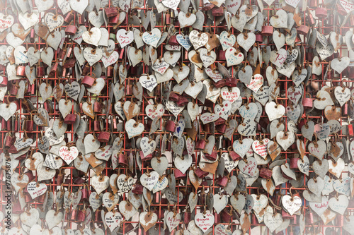 love - a metallic fence with hearts and padlocks with couples names photo