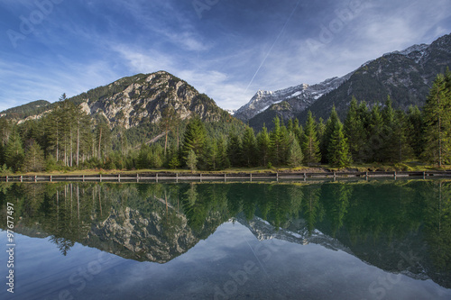 Die Bergketten der Tiroler Alpen spiegeln sich auf der glatten Oberfläche des Plansees in Österreich.