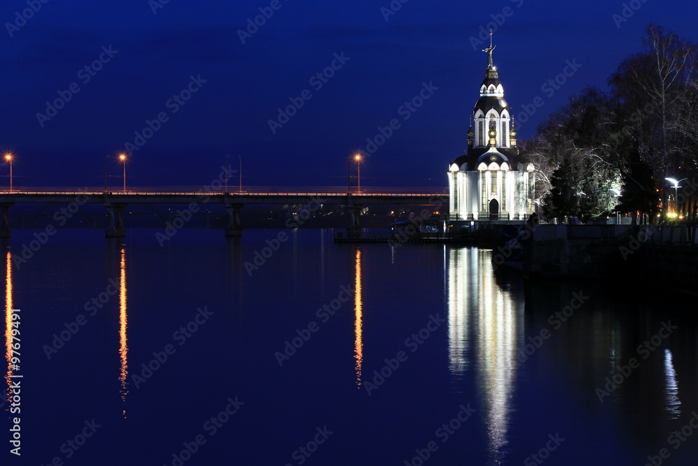 Beautiful church  with illuminating  at night. domes, evening, lanterns are reflected in water. 