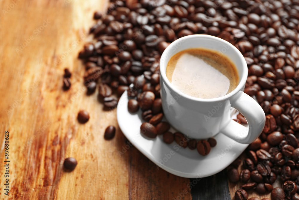 Fototapeta premium Cup of coffee and coffee grains on wooden table background