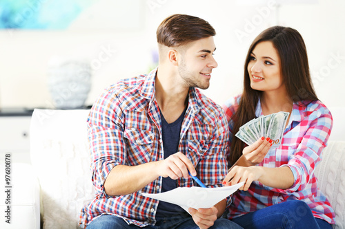 Young couple sitting and calculating bills at home
