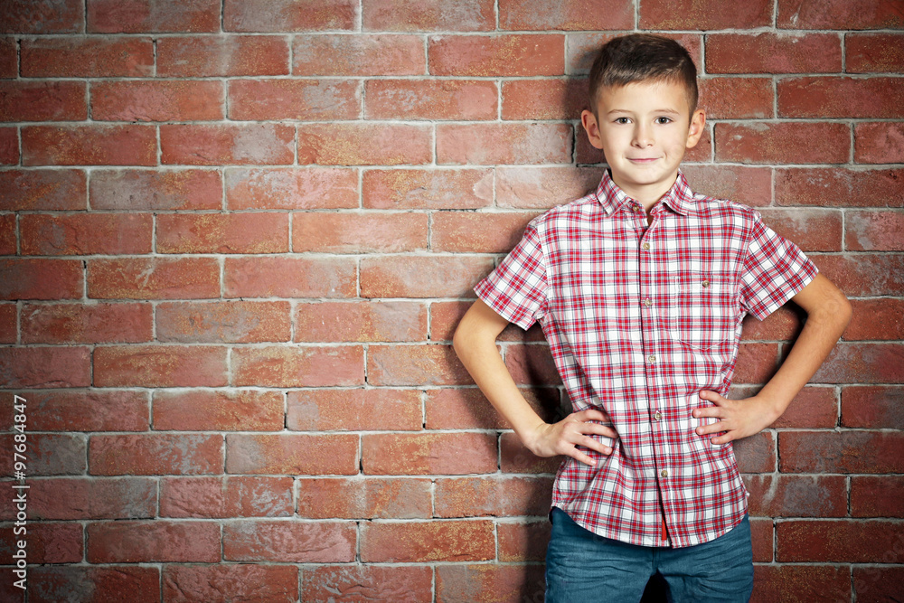 Cute little boy on brick wall background. Kids fashion concept Cute little boy on brick wall background. Kids fashion concept