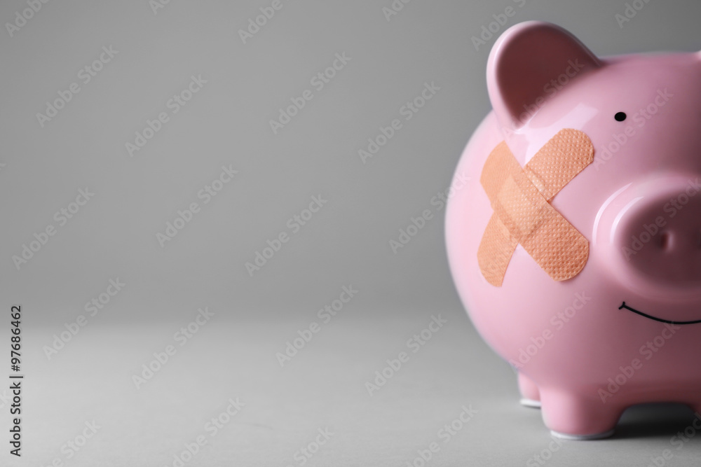 Piggy Bank with adhesive bandage on grey background Piggy Bank with adhesive bandage on grey background