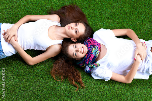 Two pretty girls lying on the fresh green grass 