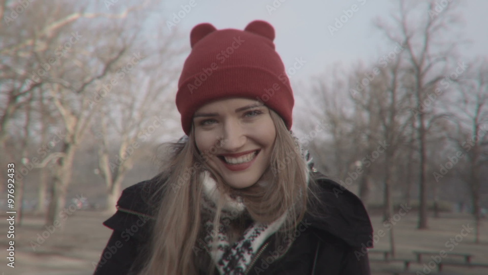 Woman with red hat looking at camera and smiling. Young beautiful woman wearing red hat in autumn/winter scenery. Woman with red hat looking at camera and smiling. Young beautiful woman wearing red hat in autumn/winter scenery.