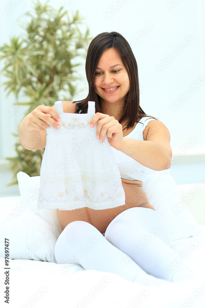 Pregnant woman contemplates the future baby dress Pregnant woman contemplates the future baby dress