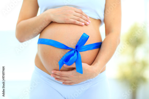 Wallpaper Mural woman holding hands on her baby bump, tied with a blue bow Torontodigital.ca