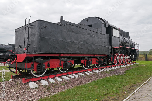Old black steam locomotive on cloudy sky background 