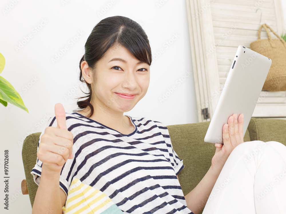 部屋でタブレットを使う女性　グッドサイン