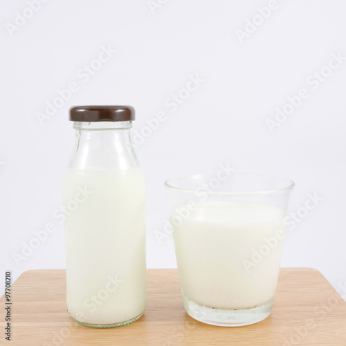The glass and bottle of fresh milk on the wooden board.