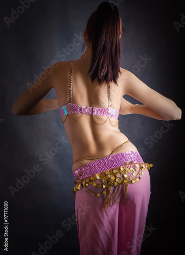 Exotic belly dancer woman with perfect body on a dark background.