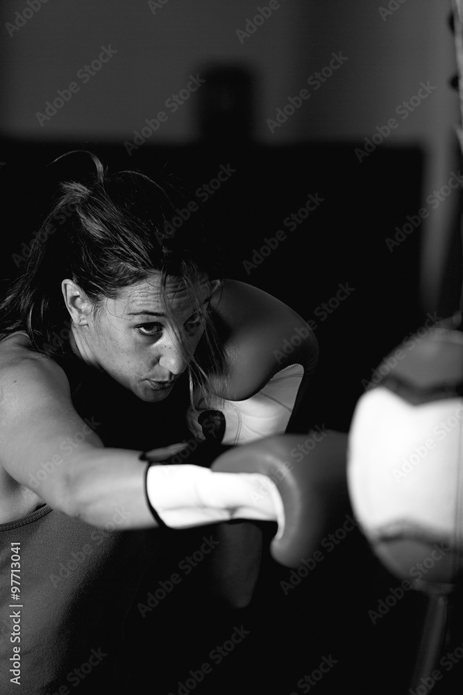 Aggressive female athlete boxing in gym Aggressive female athlete boxing in gym