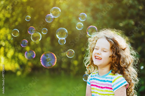 Laughing curly girl with bubbles.