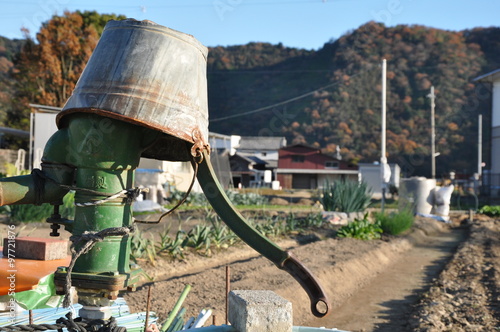 バケツをかぶった手押しポンプ