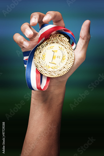 hand holding up a gold medal as a winner in a competition