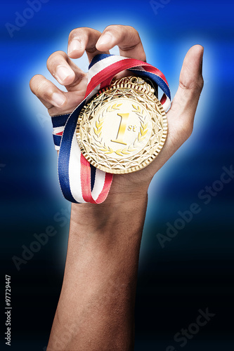 hand holding up a gold medal as a winner in a competition