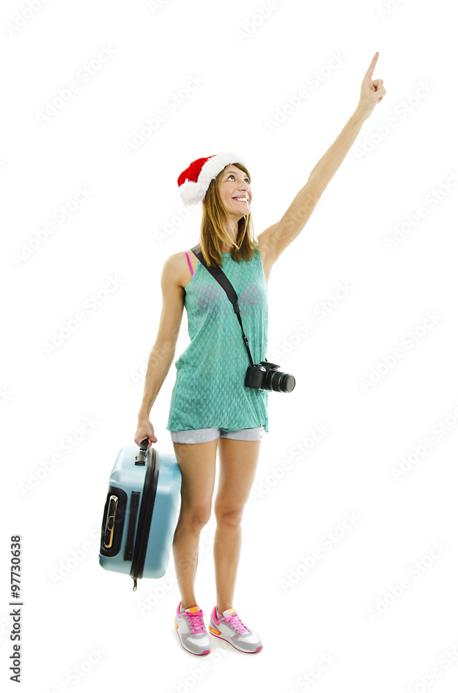 Happy traveler in santa hat with camera and suitcase going on vacation, pointing up. Isolated on white background
