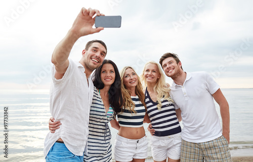 happy friends on beach and taking selfie