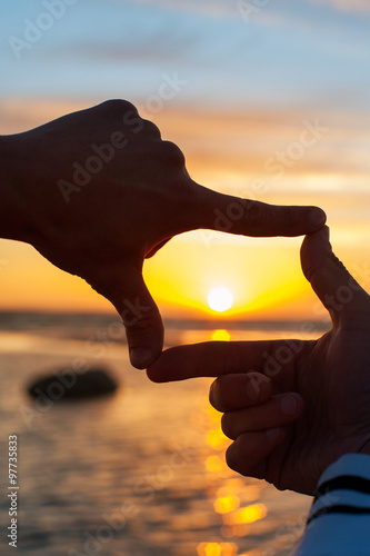 Finger frame-  imitation of capturing rays of sunlight on sunset