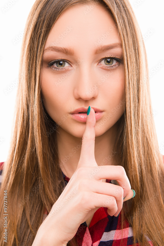 Serious young girl shows a silence gesture Serious young girl shows a silence gesture