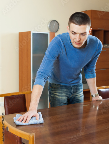 man dusting table with detergent polish at home