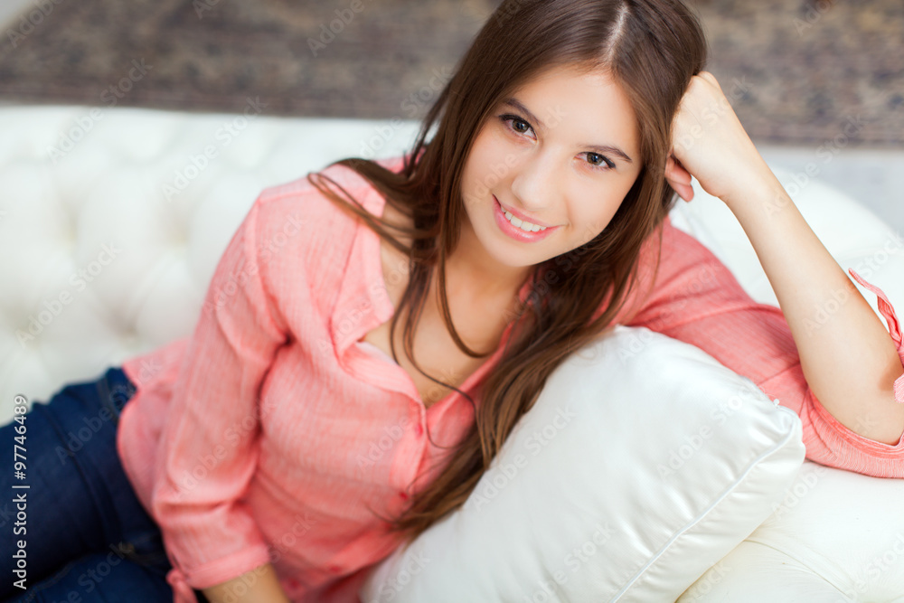 Portrait of a smiling young woman relaxing on the couch in her home