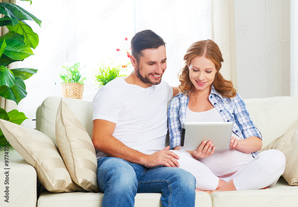 Happy parents waiting malyshayu pregnant mom and dad with tablet Happy parents waiting malyshayu pregnant mom and dad with tablet