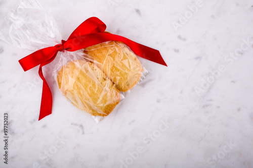 Madeleines wrapped with red ribbon on a white pastry board.