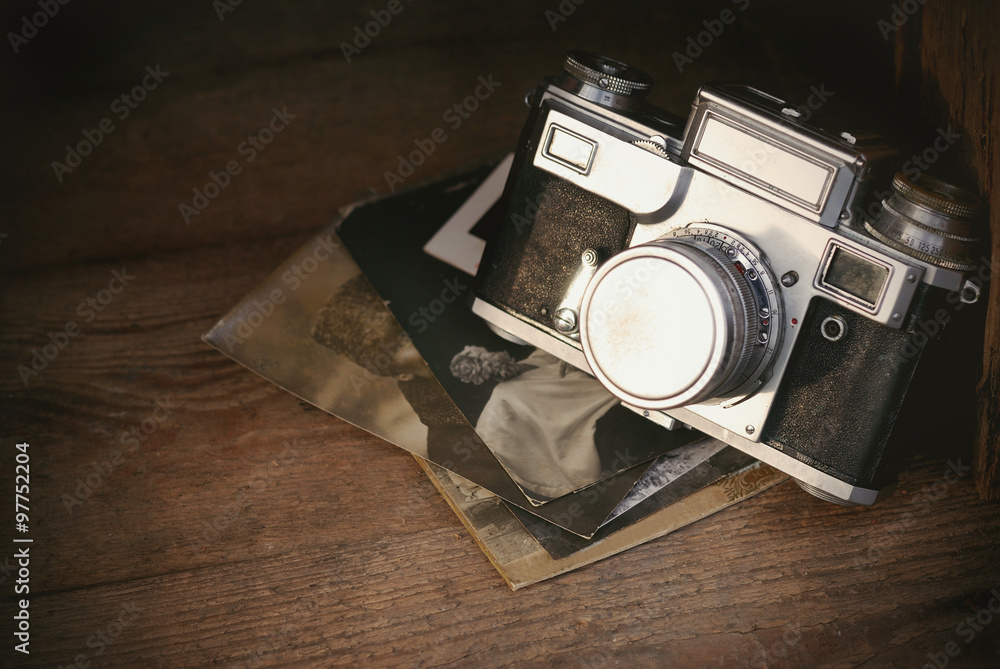 Retro camera with old photos on rustic wooden board, vintage background