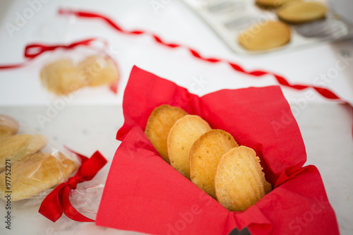 Madeleines in a red napkin on a white marble pastry board amid gift-wrapped sweets. photo