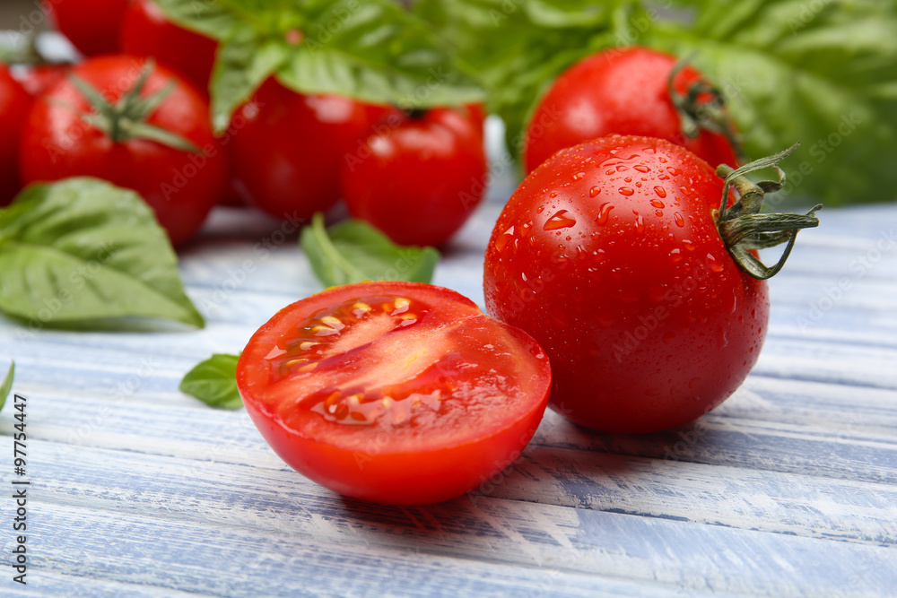 Fresh tomatoes with basil on wooden table close up Fresh tomatoes with basil on wooden table close up