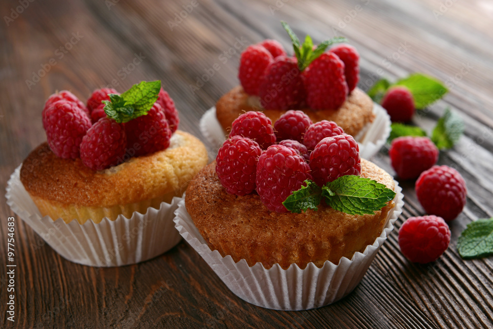 Delicious cupcakes with berries and fresh mint on wooden table close up Delicious cupcakes with berries and fresh mint on wooden table close up