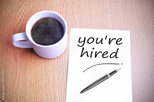 Coffee on the table with note writing you're hired