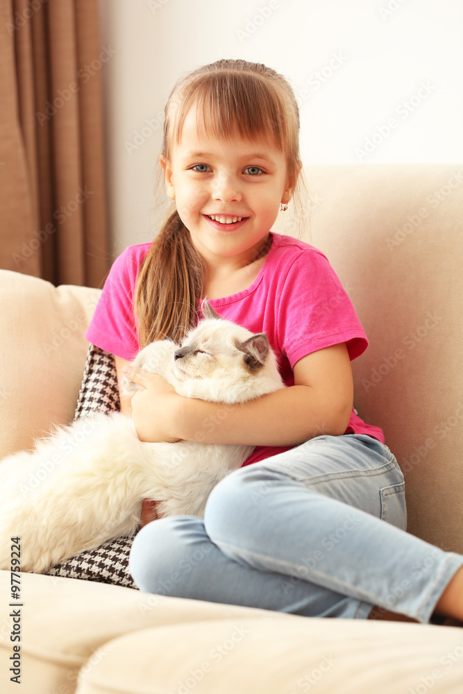 Little cute girl with kitten on sofa at home Little cute girl with kitten on sofa at home