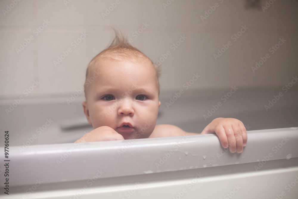 serious kid looks out of bathroom, bathing in bathroom serious kid looks out of bathroom, bathing in bathroom