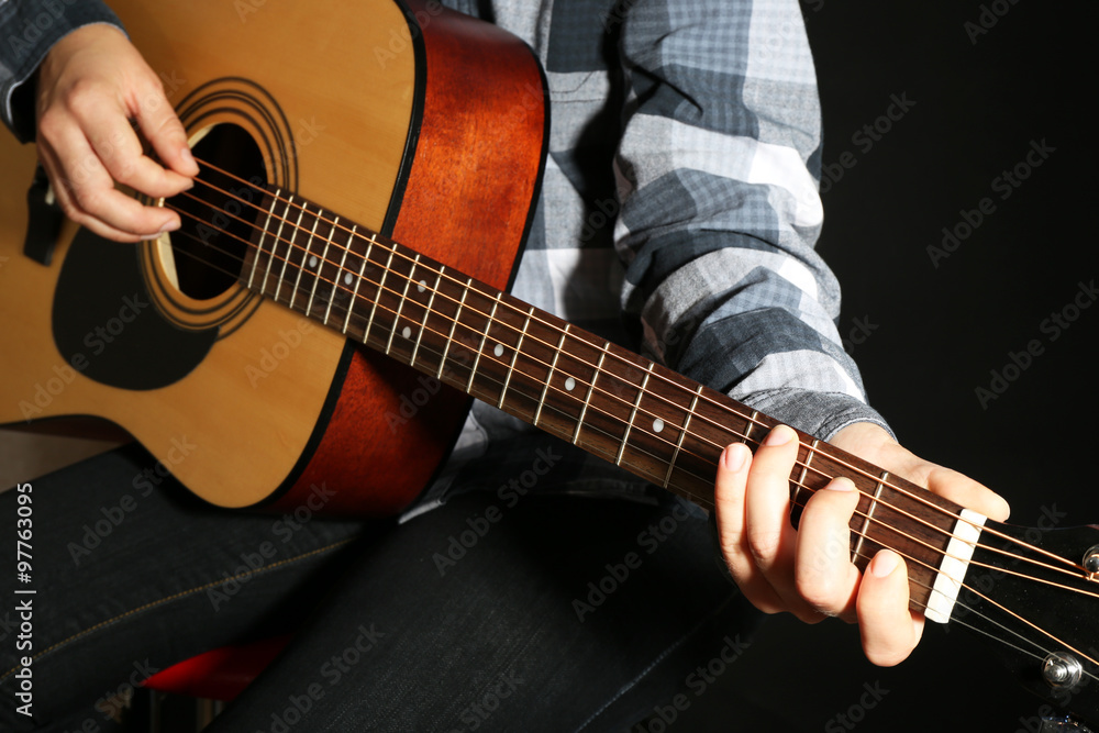 Guitarist plays guitar in dark studio, close up