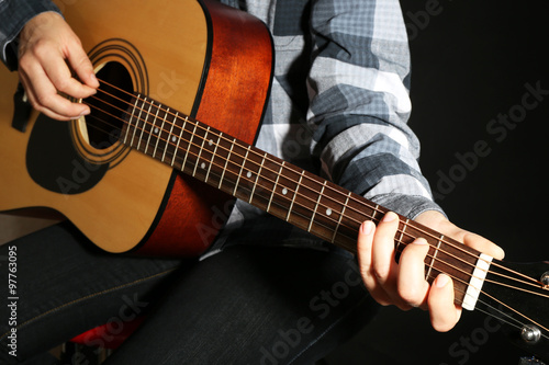 Guitarist plays guitar in dark studio, close up