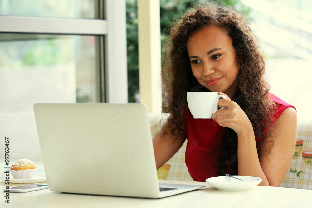 Young pretty business woman with laptop in the restaurant drinking coffee, close up Young pretty business woman with laptop in the restaurant drinking coffee, close up