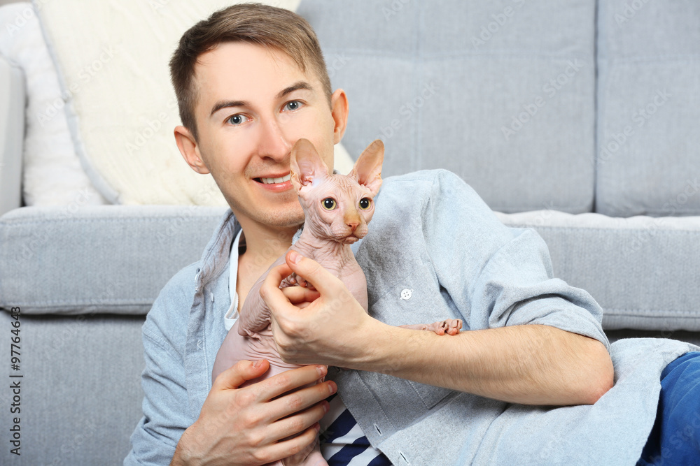 Obraz premium Young handsome man lies with cat on floor at home
