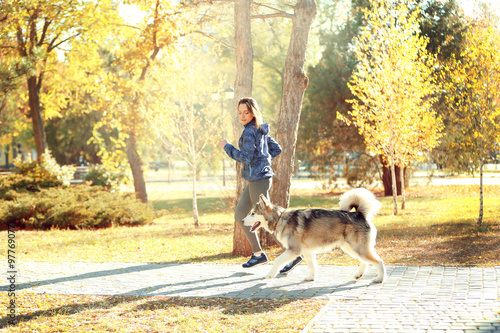 Happy young woman jogging with her dog in park © Africa Studio