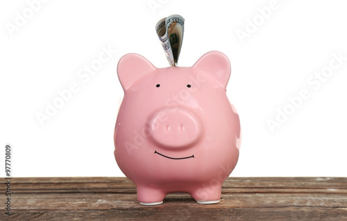 Piggy bank with banknote on wooden table, isolated on white