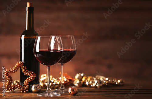 Red wine and Christmas ornaments on wooden table on wooden background © Africa Studio