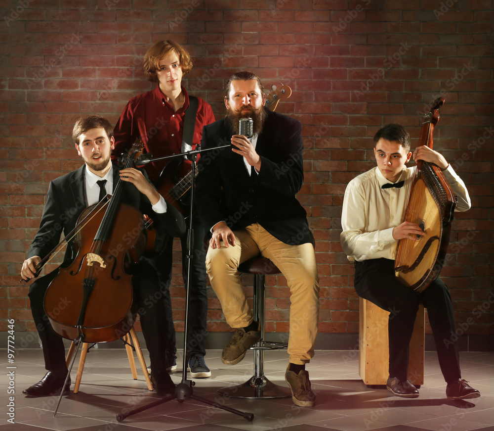 Fototapeta premium Man's musical band on brick wall background in the studio