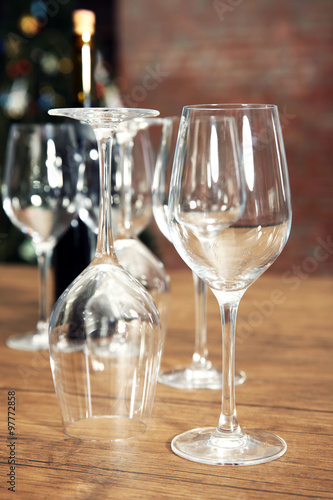Construction of empty wine glasses and bottle on wooden table against blurred background