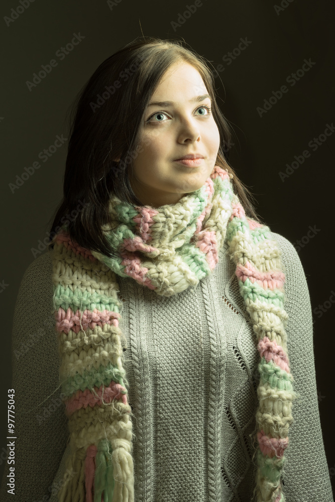Cheerful young female in a winter scarf on grey background Cheerful young female in a winter scarf on grey background