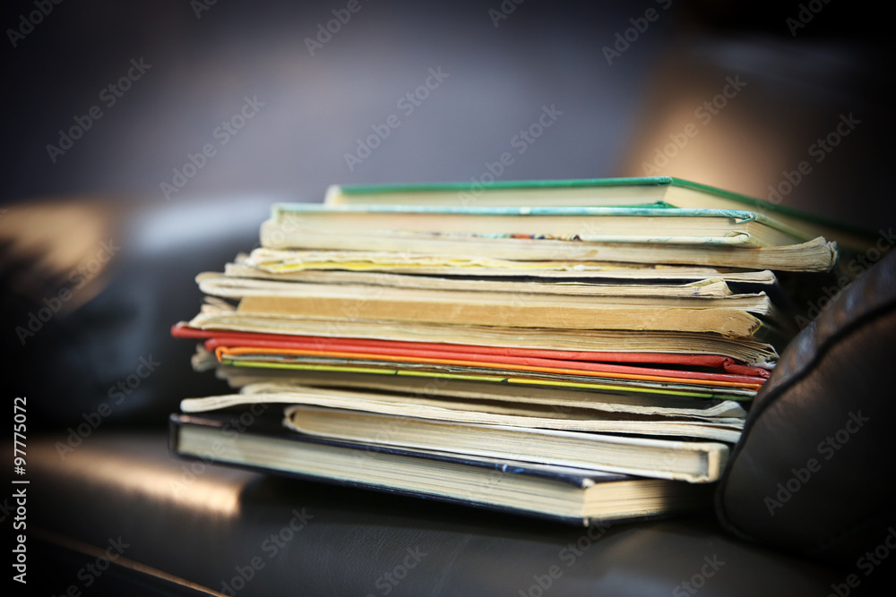 Pile of books on leather chair in the room, close up