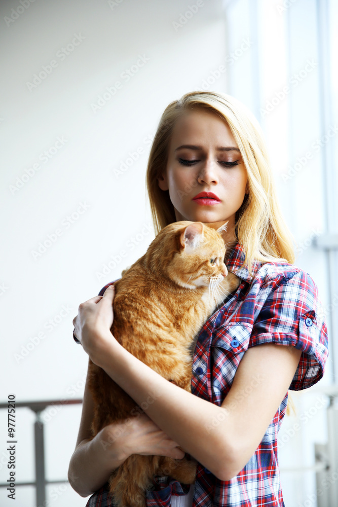 Obraz premium Young woman posing with red cat in hands, close up